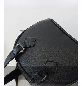 Close-up of black lychee grain leather texture and metallic hardware on kids' shell bag