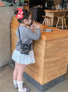 Détail d'un mini sac noir à paillettes pour enfant avec tenue chic et chaussures argent