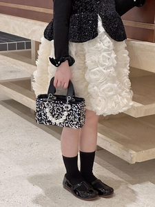 Detailed view of sequin handbag with pearl handle paired with elegant girl's dress