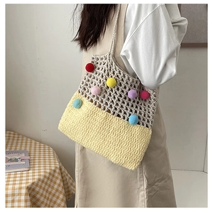 Detail of hand-woven shoulder bag featuring colorful pom-poms and yellow knit texture