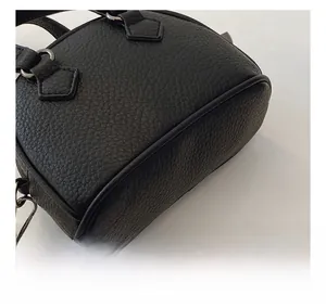 Detail shot of black litchi pattern leather and stitching on the mini shell handbag