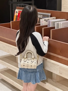 Girl carrying cream mini barrel bag with bear prints in a vintage cafe background