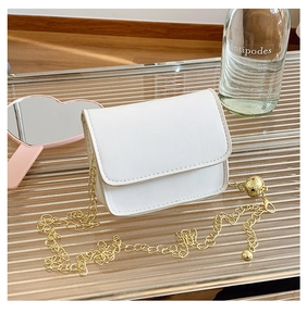 Detailed shot of white mini crossbody bag with gold chain and ball charm on glass stand