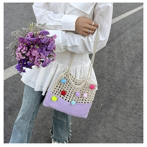Detail of crochet shoulder bag with colorful pom poms and lavender knit patchwork