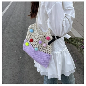 Detail of crochet shoulder bag with colorful pom-poms and two-tone woven texture