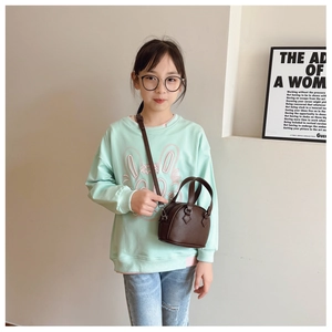Brown pebble leather shell bag for children shown with adjustable strap and handles