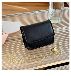 Detail of black leather mini crossbody bag with golden chain and small ball ornament