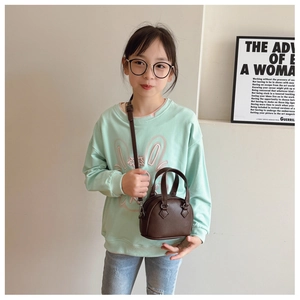 Detail of dark brown leather shell bag for kids with adjustable strap and dual handles