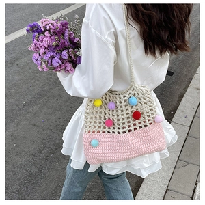 Detailed back view of a handmade crochet tote bag with colorful pom-poms on a female model