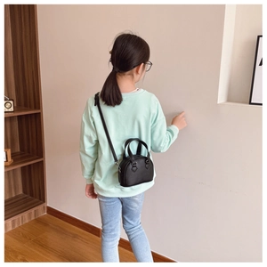 Rear view of a girl wearing a black leather shell bag with a mint green sweatshirt