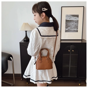 Brown shell-shaped crossbody bag with top handles shown in minimalist decor setting