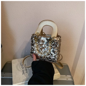 Close-up of sparkling sequin handbag with pearl chain handle and gold shoulder strap