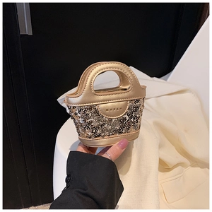 Détail du mini sac à main à paillettes dorées avec empiècement en cuir et poignée courbée