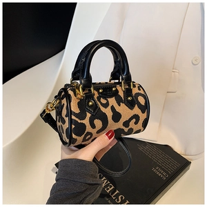 Close-up of leopard print mini barrel bag featuring black leather handles and metal zip