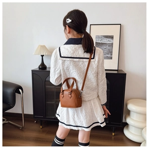 Detailed back view of mini brown shell-shaped crossbody bag with lychee grain texture