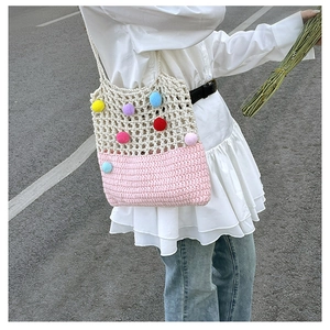 Close-up of crochet shoulder bag with colorful pom-poms and white mesh hollow design