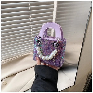 Detail of purple sequin mini bag featuring sparkling surface and large pearl handle grip