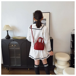 Detail showing a girl wearing a red mini shell bag with high-quality synthetic leather