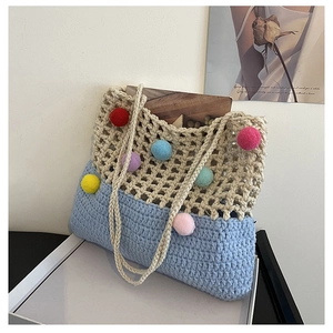 Close-up of crochet tote bag with colorful pom-poms and blue base for beach style