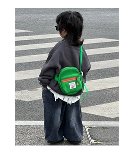 Outdoor street view of a child wearing a bright green canvas mini crossbody bag