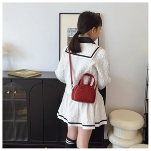 Girl wearing a mini red shell handbag with crossbody strap and litchi texture