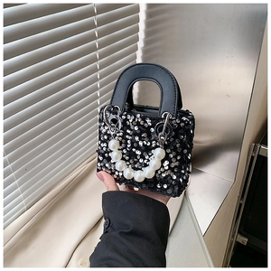Close-up of black sequined mini handbag for girls featuring a white pearl handle strap