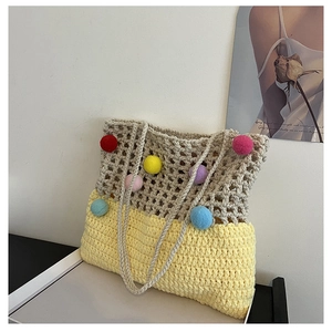 Detailed macro view of handmade woven tote bag with colorful pom-poms and dual-texture design