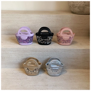 Cinq mini sacs à main à paillettes pour enfants disposés sur des marches en pierre