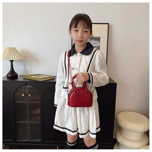 Toddler girl red shell bag with top handles and adjustable shoulder strap shown on model
