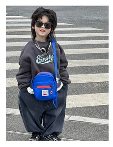 Outdoor shot of a kids bright blue crossbody bag with orange zipper and Sunny label