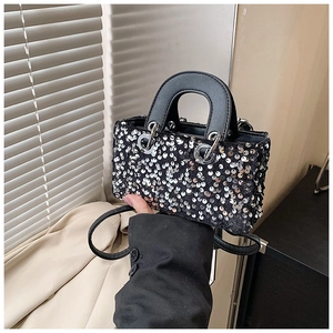 Detail of a black mini girls bag featuring sparkling silver sequins and a pearl handle