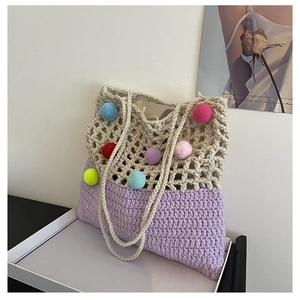Close-up of crochet tote bag featuring multi-colored pom-poms and lilac woven texture