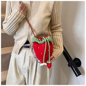 Close-up of handmade crochet strawberry bag showing detailed red knit texture and green leaves