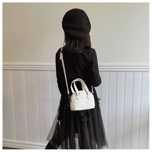 Back view of a child wearing a white shell-shaped mini bag with textured faux leather