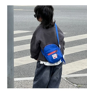 Blue canvas crossbody bag for kids with orange zipper and white patch detail