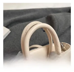 Détails des poignées renforcées et des coutures sur le sac à main en cuir beige enfant