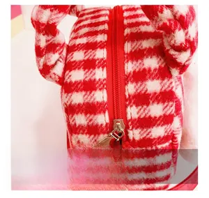 Close-up of smooth metal zipper and red leather pull on red houndstooth plush girl's bag