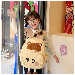 Close-up of cute teddy bear patch and house-shaped pocket on children canvas backpack