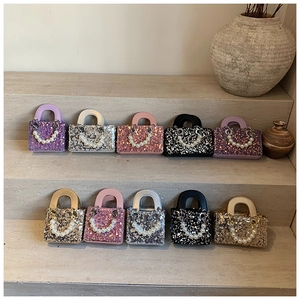 Close-up of mini sequin crossbody bags with pearl handles in multiple vibrant colors