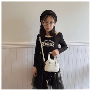 Detailed view of kids white shell bag with litchi texture and detachable strap
