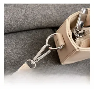 Détail du crochet métallique et de la texture cuir sur un mini sac à bandoulière crème