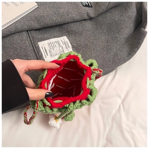Close-up of handmade crochet strawberry bag interior with red lining and flower charm
