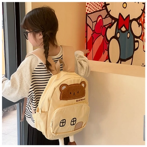 Detailed back view of a cute bear house canvas backpack worn by a small child