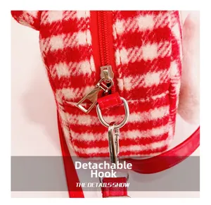 Detail showing the red plaid plush bag with detachable bright metal hook and D-ring