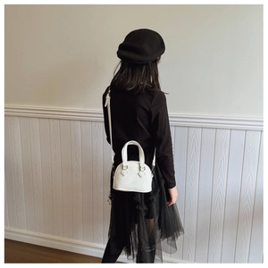 Toddler model carrying a small white shell-shaped bag with lychee grain texture