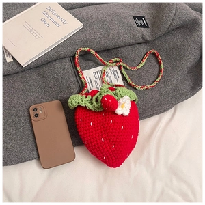Detailed close-up of a handmade crochet strawberry crossbody bag with green leaf design