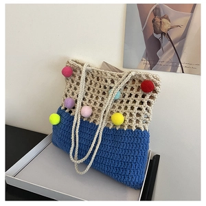 Detail showing hand-woven crochet bag with colorful pom-poms and beige mesh pattern