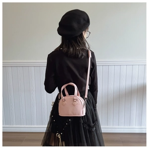 Rear view of a child wearing a pink pebble leather mini shell bag with silver hardware