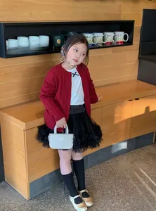 Gros plan d'un enfant portant un gilet rouge en maille avec un tutu noir et souliers dorés