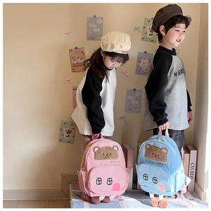 Detail of cute house-shaped backpacks with plush bear patches for toddler boys and girls